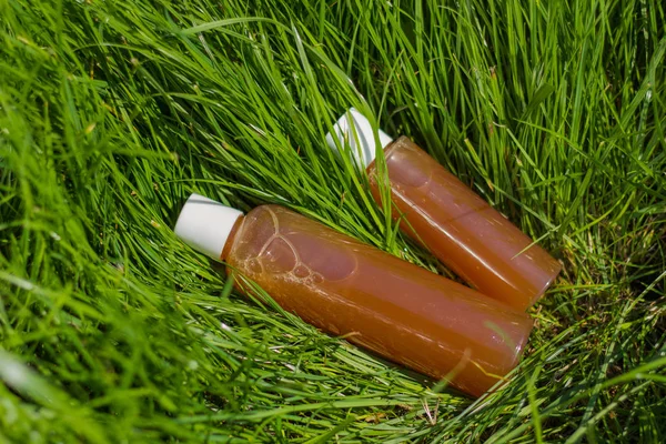 Büyük ve küçük plastik şişe şampuanla çimenlerin üzerinde yatıyordu.