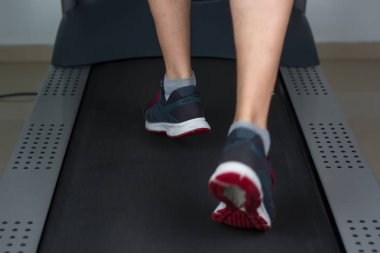 Spor salonunda koşu bandı üzerinde yürüyen adam ayak