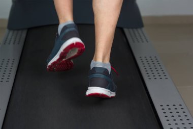 Spor salonunda koşu bandı üzerinde yürüyen adam ayak