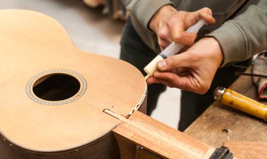 Grodno, Belarus - 18 Ocak 2017. Ciddi profesyonel gitar üreticisi bitmemiş gitarla workshopthe işçi çalışma stüdyoda gitar gitar imalatı için tutkallar