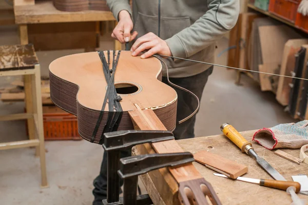 Grave chitarrista professionista che lavora con chitarra incompiuta in officina — Foto Stock