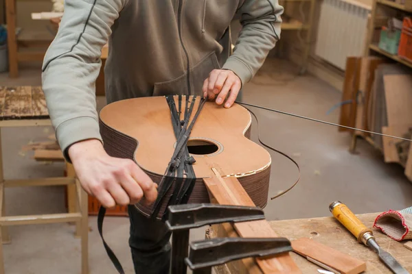 GRODNO, BELARO - 18 GENNAIO 2017. Grave chitarrista professionista che lavora con chitarra incompiuta in officina — Foto Stock