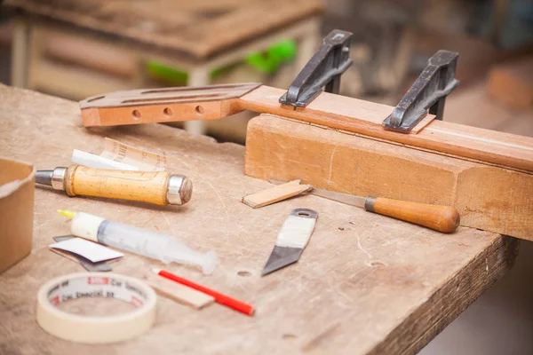 Unfertige Gitarre auf Tisch in Werkstatt mit Werkzeug — Stockfoto