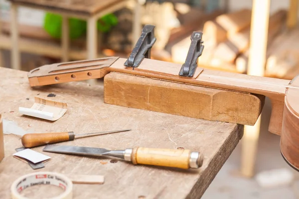 Unfinished guitar on table at workshop with tools — Stock Photo, Image