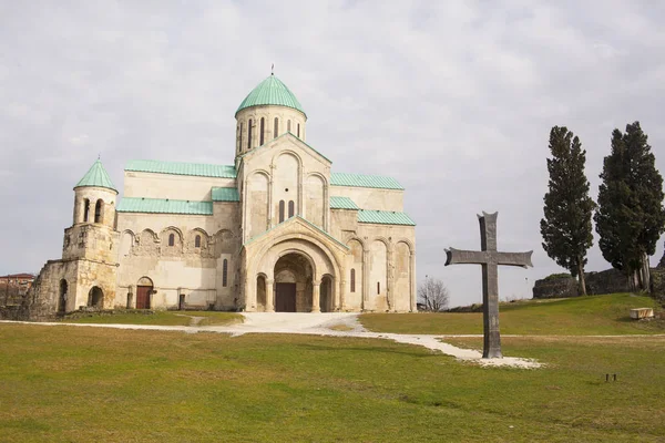 Catedral da Dormição, ou Catedral de Kutaisi, mais comumente conhecida como Catedral de Bagrati contra fundo azul do céu. Cruz de bronze em primeiro plano . — Fotografia de Stock