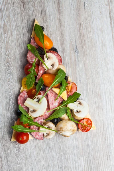 Composition créative d'ingrédients tomates, fromage, salami, champignons, roquette, olives sous la forme d'une tranche de pizza — Photo