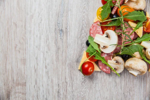 Composición creativa de ingredientes tomates, queso, salami, champiñones, rúcula, aceitunas en forma de rebanada de pizza — Foto de Stock