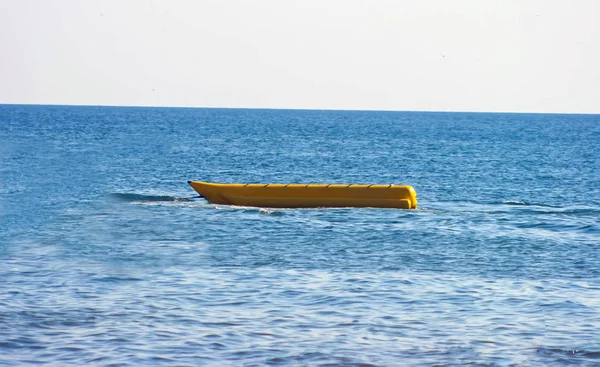 yellow banana ride rocks on the sea waves