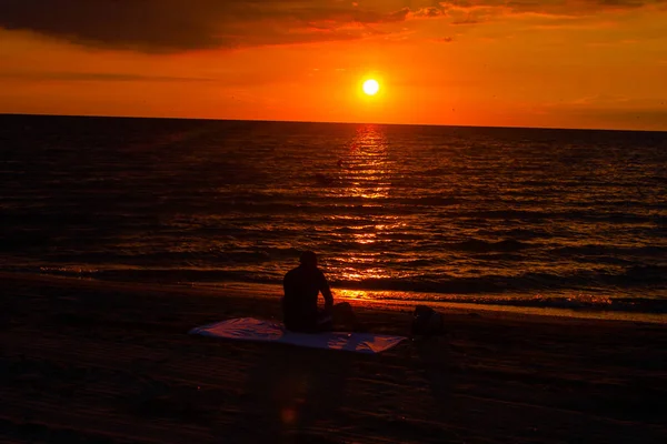 男人坐在沙滩上看日出 — 图库照片