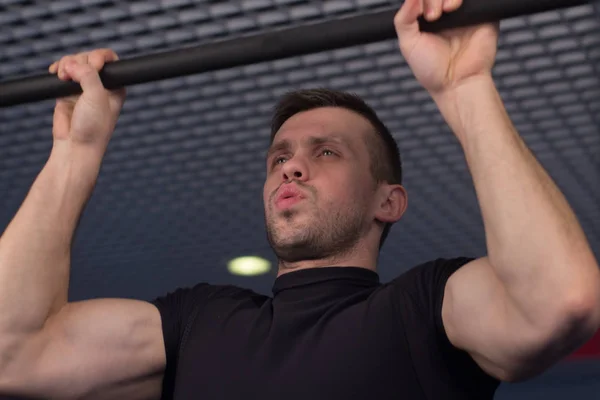 Um jovem fazendo pull ups no ginásio — Fotografia de Stock