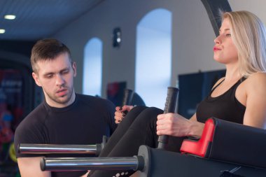 Bacak yapıyor genç kadın atlet spor salonunda egzersiz eğitmen ile yükseltir.