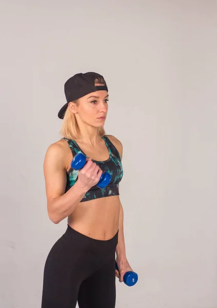 Seksi genç Atletizm kız dumbbells basın egzersizleri yapıyor. Fitness kaslı kadın siyah spor giyim egzersiz jimnastik salonu bankta — Stok fotoğraf