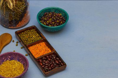 Kırmızı ve yeşil mercimek ve fasulye tanecikleri bir karıştırıcıda yakın plan masa görüntüsünde, mavi arka plan,