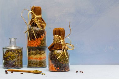  Farklı renkte fasulye ve mercimek içeren üç kavanoz mavi arka planda, yatay, uzay