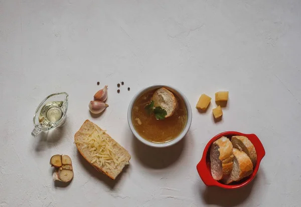 Sopa de cebolla en un tazón blanco, con rebanadas de baguette y queso sobre un fondo blanco — Foto de Stock