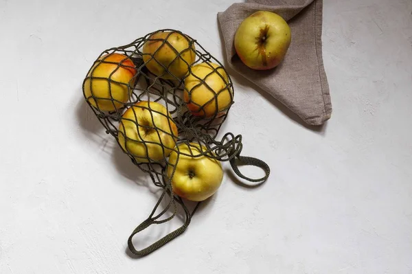 Un sac à ficelle avec des pommes jaunes et une pomme sur une serviette en lin gris sur le dessus horizontalement — Photo