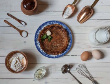 Masanın ortasında mavi bir tabakta ince krepler ve yemek aksesuarları.