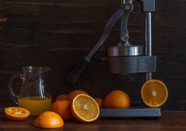 whole and sliced oranges, a jug of fresh juice, and a citrus juice press