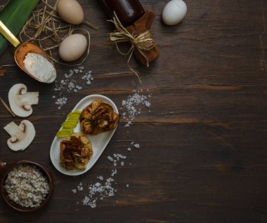 mushroom julienne in bags of thin wheat pancakes on a dark wooden table with ingredients for cooking