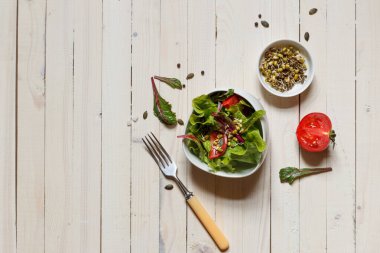 Sağlıklı pancar yaprağı salatası, kiraz, balkabağı tohumu, fasulye ve kenevir filizleri beyaz bir kasede hafif arka planda, yatay olarak.