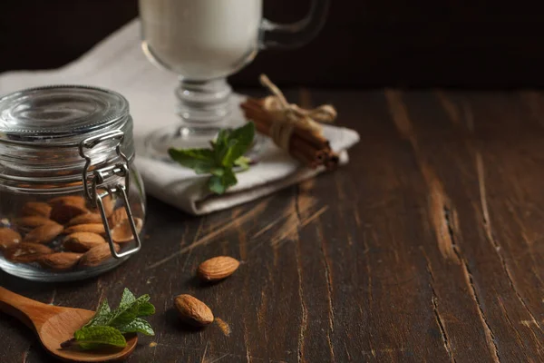 Almendras Pequeño Frasco Vidrio Cerca Menta Fresca Una Mesa Madera — Foto de Stock