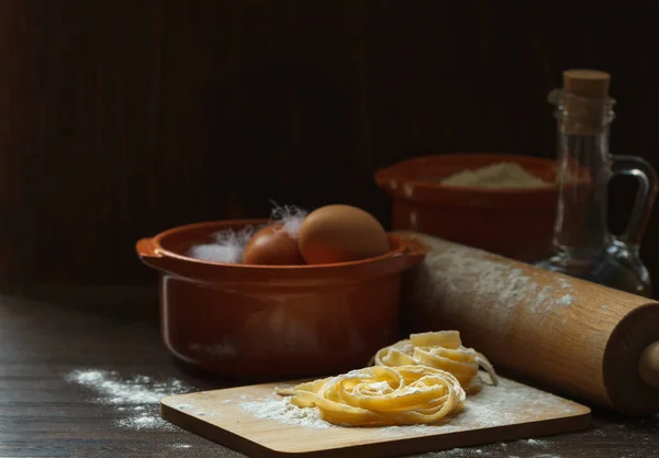 Pastas caseras en una tabla con harina e ingredientes para cocinar, low key — Foto de Stock