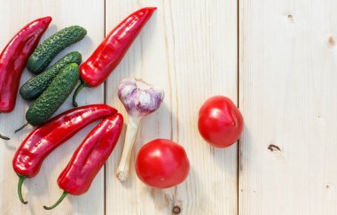 Taze salatalık, kırmızı tatlı paprika ve açık ahşap zemin üzerinde taze sarımsak.