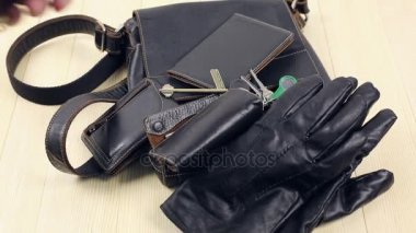 Erkekler için deri eşyalar. Adam ev ve bırakır onun deri aksesuarlar geldi ahşap bir masa, bir çanta, önemli bir dava, bir şartlı tahliye cüzdan, eldiven