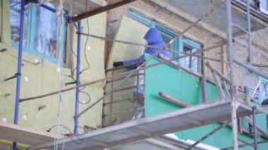 İşçiler ve sıcak cephe bina onarım. Eski ev mineral yün ile sıkıştırılır ve binanın dış kaplı. Sigortası olmayan yükseklikte çalışma