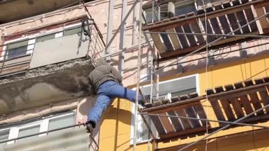 İşçiler ve sıcak cephe bina onarım. Eski ev mineral yün ile sıkıştırılır ve binanın dış kaplı. Sigortası olmayan yükseklikte çalışma