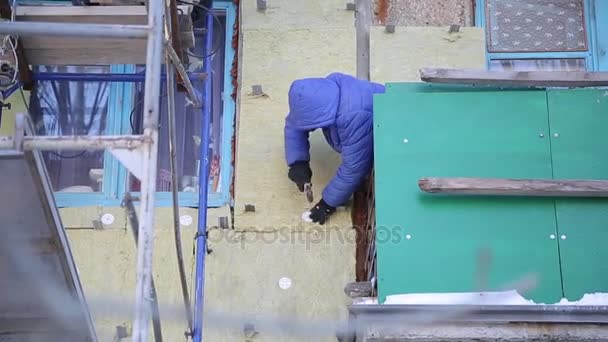 Workers warm and repair the facade of the building. The old house is compacted with mineral wool and the exterior of the building is lined. Work at height without insurance — Stock Footage Workers Warm Repair Facade Building Old House Compacted Mineral Wool Stock Video