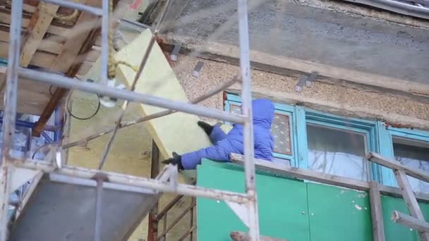 工人们热情地修理建筑物的正面 老房子用矿棉压实 建筑的外部是内衬 在没有保险的高度工作 — 图库视频影像