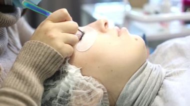 Hacimsel kirpik güzellik salonunda genişletir. Sarışın kızın önünde kirpik artan yordamı bir güzellik salonu bir usta tarafından yapılır