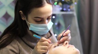 Hacimsel kirpik güzellik salonunda genişletir. Sarışın kızın önünde kirpik artan yordamı bir güzellik salonu bir usta tarafından yapılır