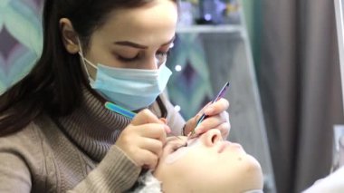 Hacimsel kirpik güzellik salonunda genişletir. Sarışın kızın önünde kirpik artan yordamı bir güzellik salonu bir usta tarafından yapılır