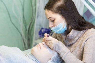 Sarışın kızın önünde kirpik artan yordamı bir güzellik salonu bir usta tarafından yapılır