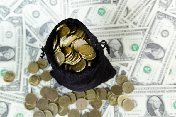 Een zak munten ligt op een stapel van dollar. — Stockfoto