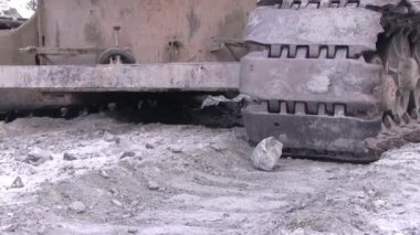 Ağır traktör tırtıl bir taş vurur. Ağır bir ekskavatör bir taş üstünde belgili tanımlık yol sürmek ve onu dövüyor.