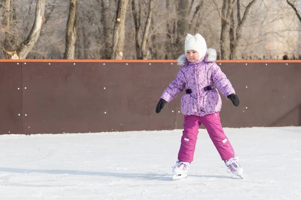 La niña se ríe y patina sobre el hielo . — Foto de Stock