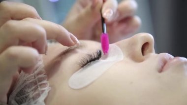 Genç bir kız bir güzellik salonu kirpik artırır. Sarışın kız artan ve hacimsel kirpik uzantıları süreci.