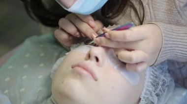 Genç bir kız bir güzellik salonu kirpik artırır. Sarışın kız artan ve hacimsel kirpik uzantıları süreci.