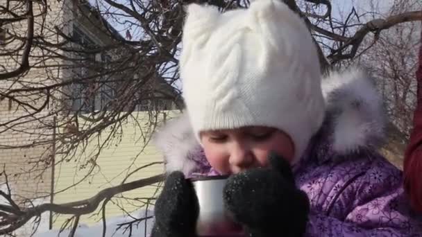 美しい少女は 冬の街で茶を飲みます 冬の服の女の子は冬ピクニックに熱いお茶を飲む — ストック動画