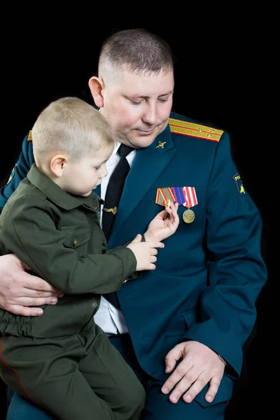 Malý chlapec ve vojenské uniformě se dívá na vojenské medaile. — Stock fotografie
