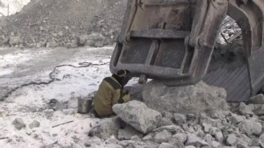 Bir çalışma metal kaynakçı bir taş ocağında çalışıyor. Kaynak maskesi ve bir elektrot yardımıyla tulum işçi Ekskavatör Kepçe onarır.