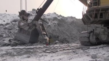 Bir çalışma metal kaynakçı bir taş ocağında çalışıyor. Kaynak maskesi ve bir elektrot yardımıyla tulum işçi Ekskavatör Kepçe onarır.