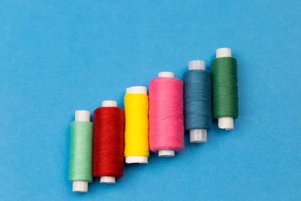 Coils with multi-colored threads on a blue background. — Stock Photo, Image