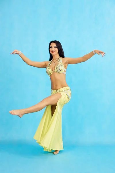 Чарівна танцівниця виконує східний танець живота на синьому фоні . — стокове фото
