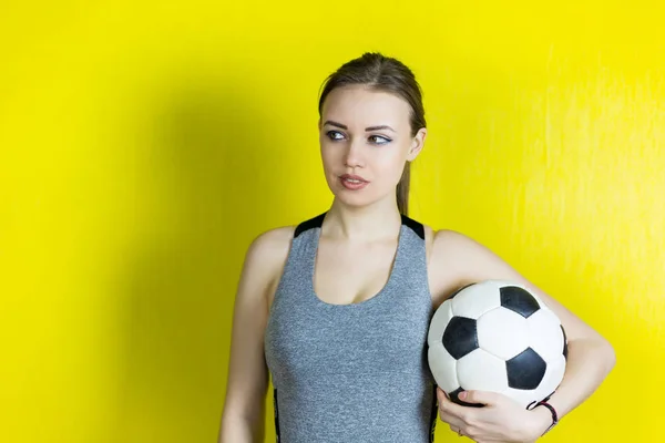 Девушка с футбольным мячом на желтом фоне . — стоковое фото
