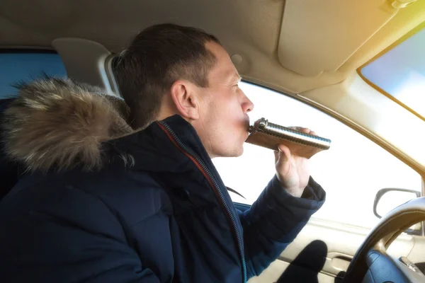 Alkolik sürücü bir araba sürüş sırasında konyak içer.