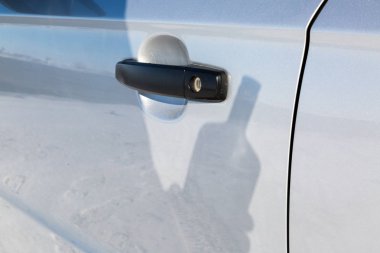 Bir el ile bir şişe alkol arabanın kapısını açar.